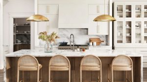 Bye Bye Basic Bar Tabourets – Ces 16 designs élégants sont la clé pour rehausser les sièges de votre îlot de cuisine A white kitchen with a wooden island and cane back barstools