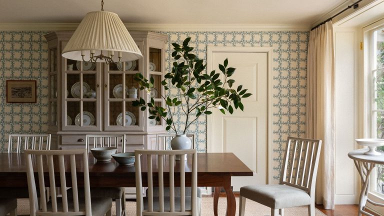 24 pièces pour apporter l’esthétique du jardin de campagne anglais à l’intérieur – et la laisser se répandre à nouveau Sun-drenched dining room featuring blue-and-white rose-motif wallpaper, airy white dining chairs, a pleated pendant light, and a large potted plant