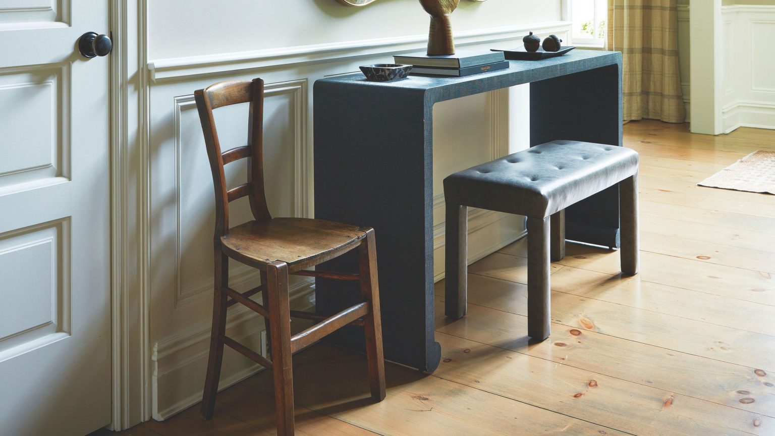 24 tables d’entrée minces qui transforment même les couloirs exigus en moments de conception sans encombrement A cozy entryway in a colonial-style home, featuring low-slung a mid-century style chair, bench, and console table topped with various objects