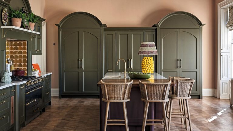 a large olive green kitchen with arched cabinetry and warm dusty pink walls