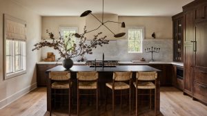Ce sont les 3 meilleures couleurs de peinture pour les cuisines avec armoires en bois, selon les designers qui les ont toutes essayées A kitchen with wooden cabinets, a black island, and white walls