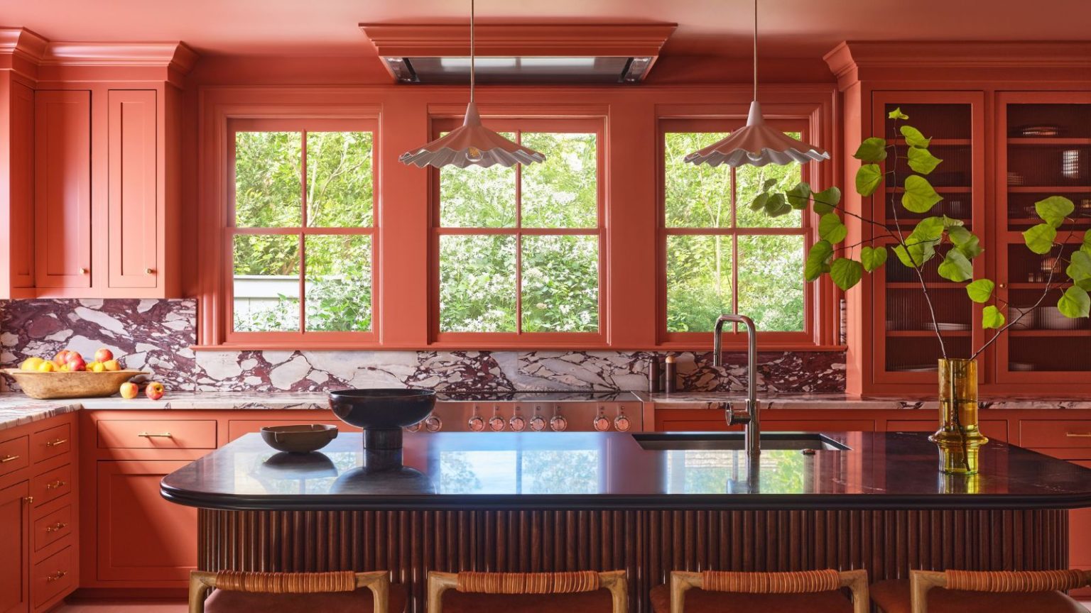 Les cuisines en terre cuite sont de retour – Voici comment utiliser cette couleur nostalgique sans surcharger la pièce A large color drenched terracotta kitchen with a fluted wood island and marble countersplash