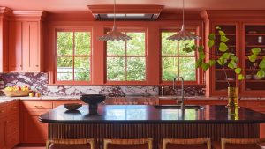 Les cuisines en terre cuite sont de retour – Voici comment utiliser cette couleur nostalgique sans surcharger la pièce A large color drenched terracotta kitchen with a fluted wood island and marble countersplash