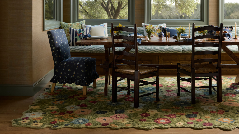 a dining room with a bold floral rug, a dining table, a banquette bunch, and grasscloth wallpaper