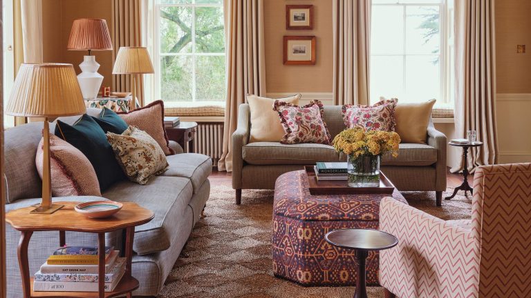 Cette vieille maison remonte peut-être aux années 1700, mais son style ludique est parfait pour la vie de famille moderne – vous devriez voir la couleur du garde-manger an English country living room with a woven rug, two neutral couches, patterned pillows, patterned otoman and a pattern armchair