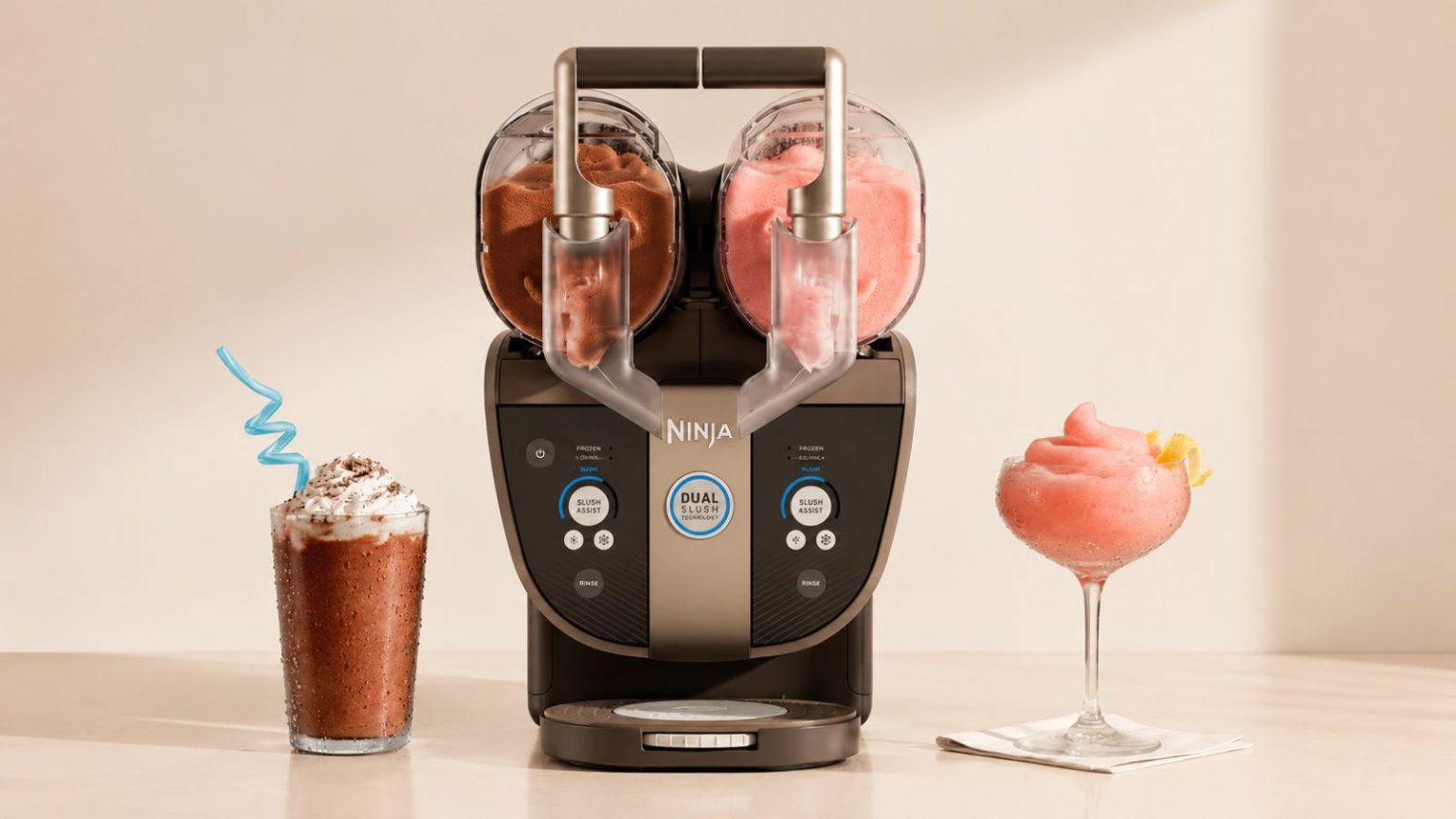 A black Ninja SLUSHi twist machine, with two dispensers, one filled with cola slush, the other with a pink slush. A glass of each on either side.