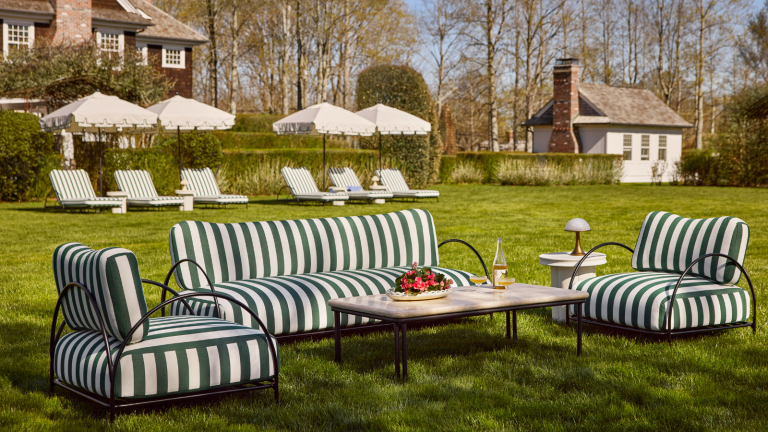 a backyard with a sitting area with furniture in green and white stripes, and six chaise lounge chairs off in the distance