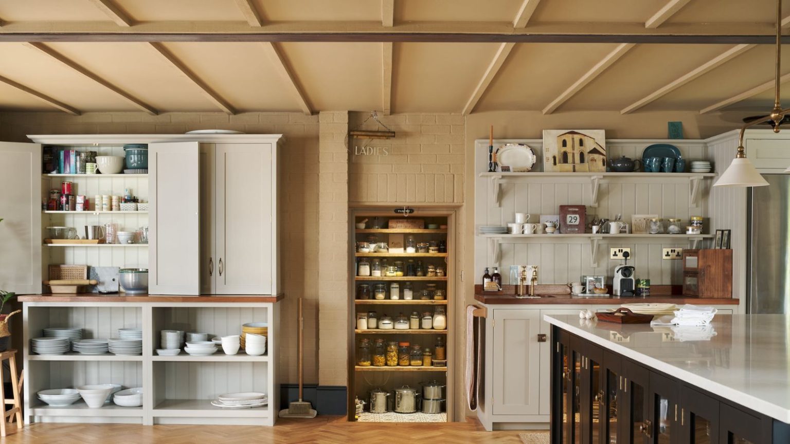 Large kitchen pantry with open shelving to the right, alcove shelving centrally, and cabinet with doors open to the left