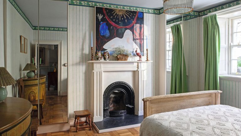 Cette maison de ville autrefois sombre a été transformée par ce que les concepteurs appellent « l’effet non beige » a large bedroom with a victorian fireplace, green and white striped walls with alcove closets with mirror fronts