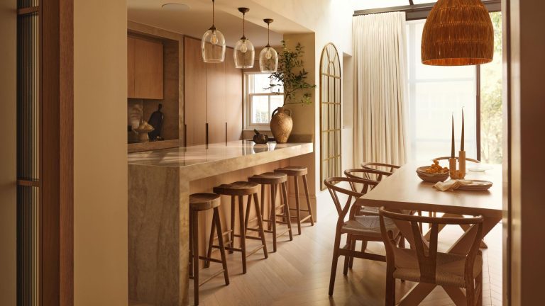 Cette vieille maison fragmentée a été complètement dépouillée – et son véritable charme a finalement émergé a European wabi-sabi style kitchen with oak cabinetry, floors, and furniture with a large rattan pendant