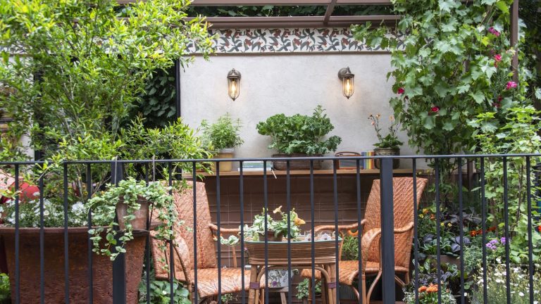 Balcony garden with two vintage brown wicker chairs, surrounded by lots of pots