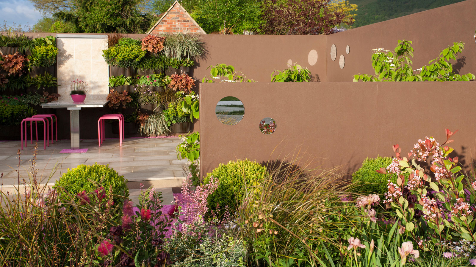 aménagement de jardin avec mur végétal, terrasse, murets, salon de jardin et parterres de fleurs