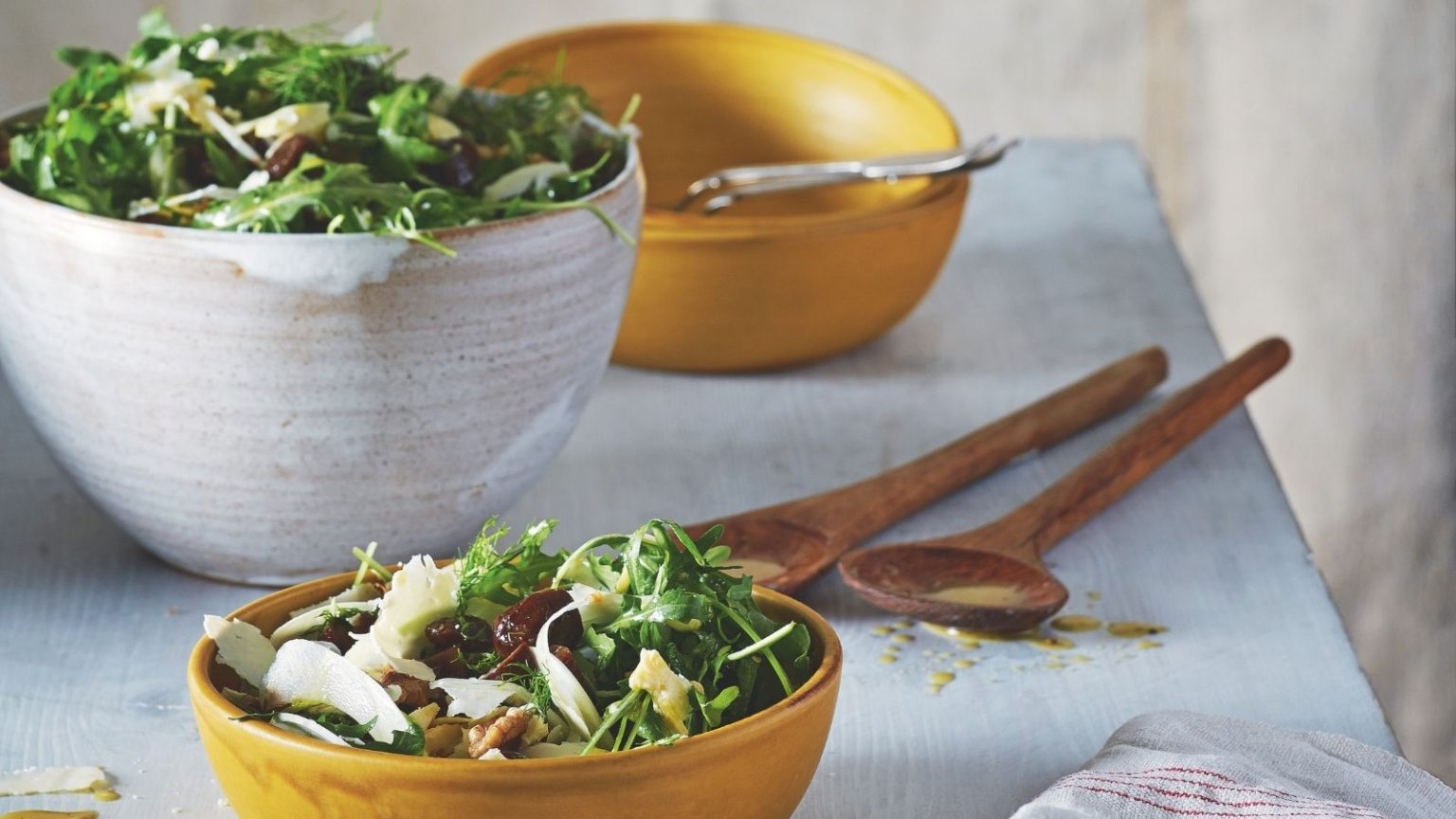 Comment faire pousser un jardin de salades en un mois – Tout ce que vous pouvez encore semer maintenant et manger quatre semaines plus tard Table with white ceramic serving bowls and yellow ceramic bowls of salad