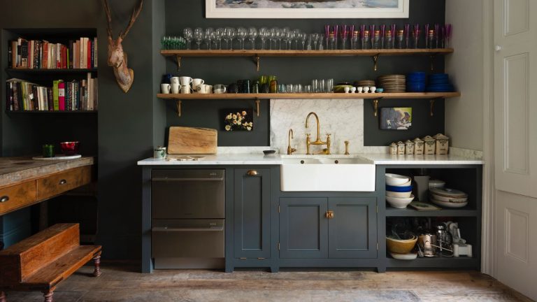 Arrêtez de peindre votre petite cuisine en blanc ! Ces 6 teintes tendance sont plus excitantes et fonctionnent toujours dans un petit espace dark blue kitchen open plan, open shelving with glassware, marble backsplash and countertop, white butler sink, wooden floorboards, deVOL