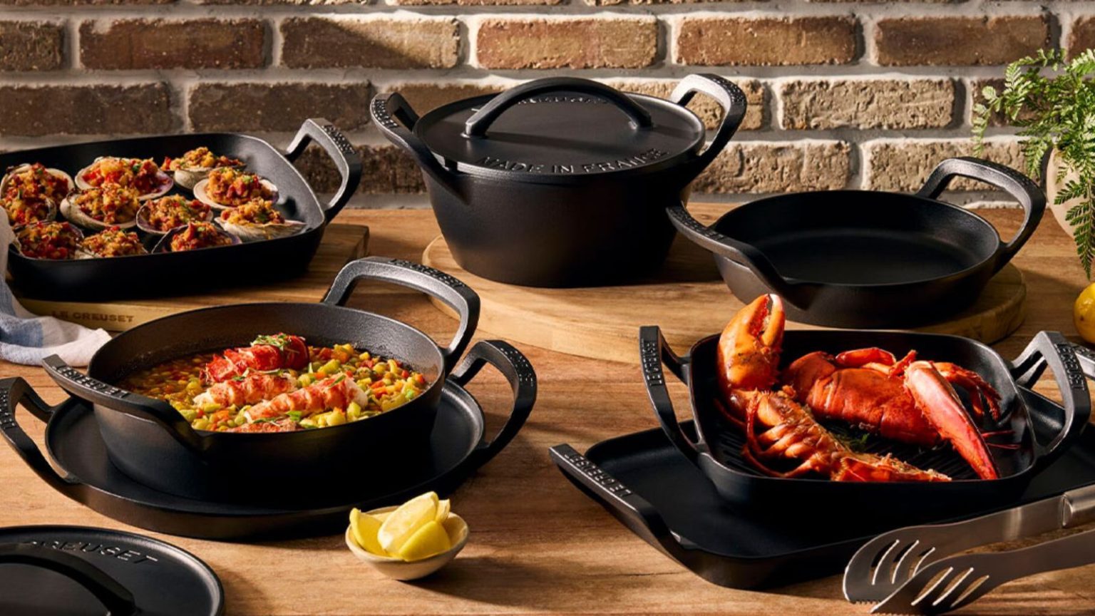 Si vous détestez attendre que le gril chauffe, ce joyau Le Creuset à dessus plat est la solution la plus rapide pour un hébergement plus facile Le Creuset Alpine Collection on a wooden outdoor table.