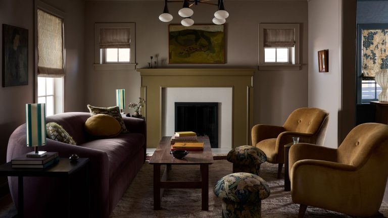 Les designers remplacent discrètement les poufs par des mini tabourets – ils sont tout aussi fonctionnels mais bien meilleurs pour les petits espaces a dark moody living room with a green fireplace, curved dark sofa, two brown armchairs and small floral mushroom stools