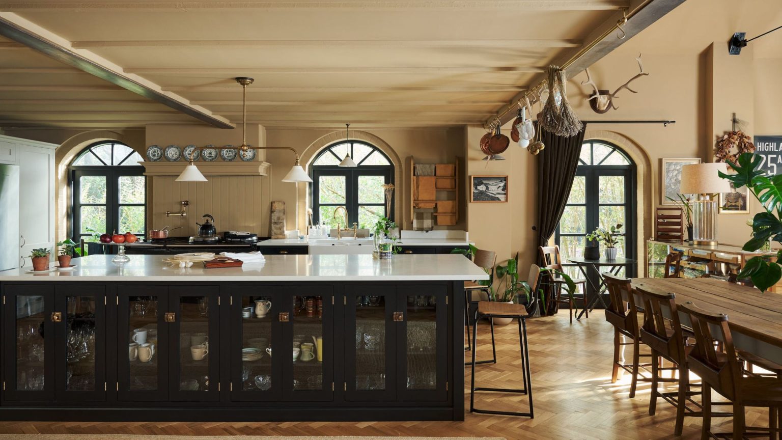 A historic home kitchen with beige walls, a dark island, and brass rails throughout