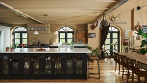 A historic home kitchen with beige walls, a dark island, and brass rails throughout