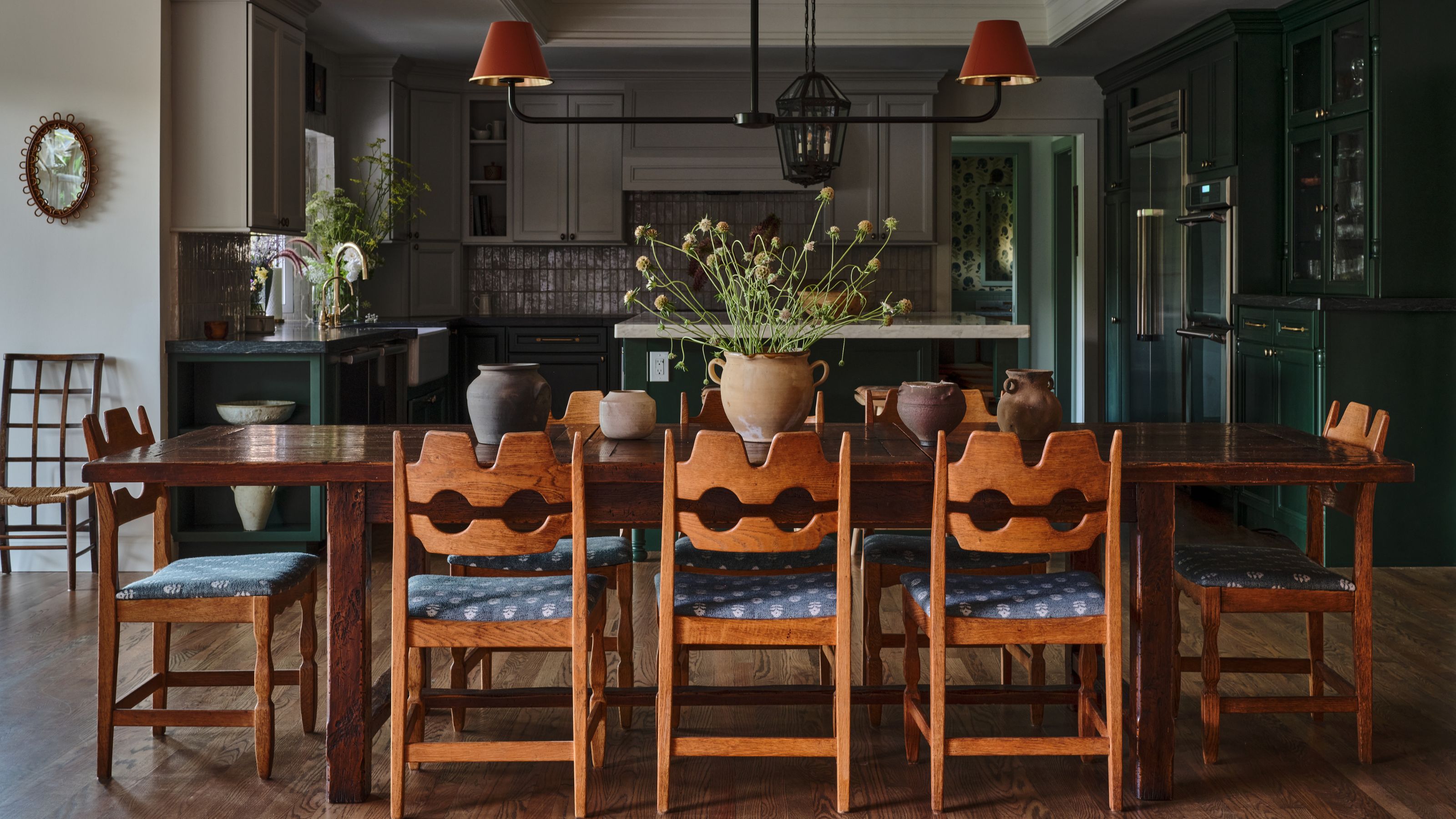 une salle à manger avec des chaises en pin suédois d'époque donnant sur une cuisine ouverte vert foncé