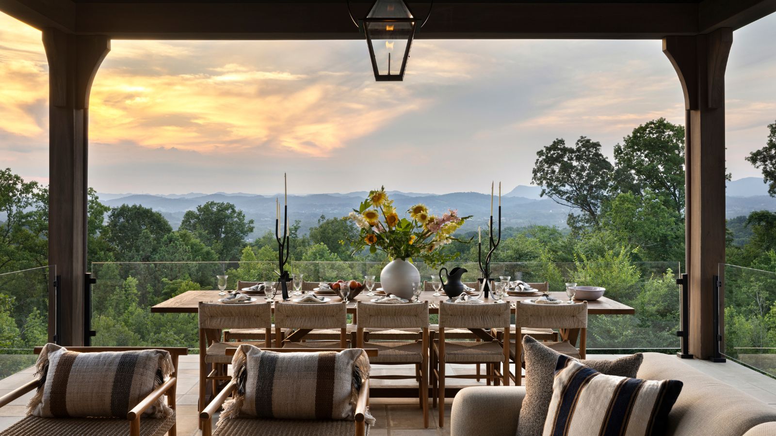 Porche arrière surélevé avec fauteuils et table à manger offrant une vue sur le coucher de soleil sur les collines
