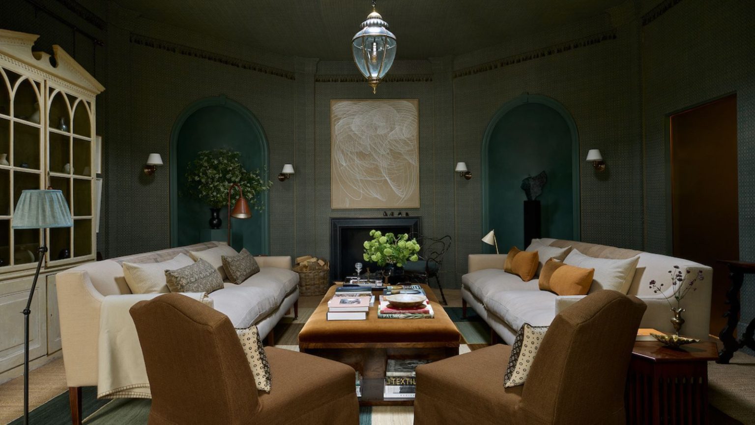 Ces 5 tendances de couleurs ont dominé WOW!house 2026 – et elles devraient être partout cette année Living room with blue grasscloth walls, alcoves with statues, a velvet brown coffee table with books on top, cream linen sofas, slipcovered brown armchairs, am armoire with books and a glass pendant