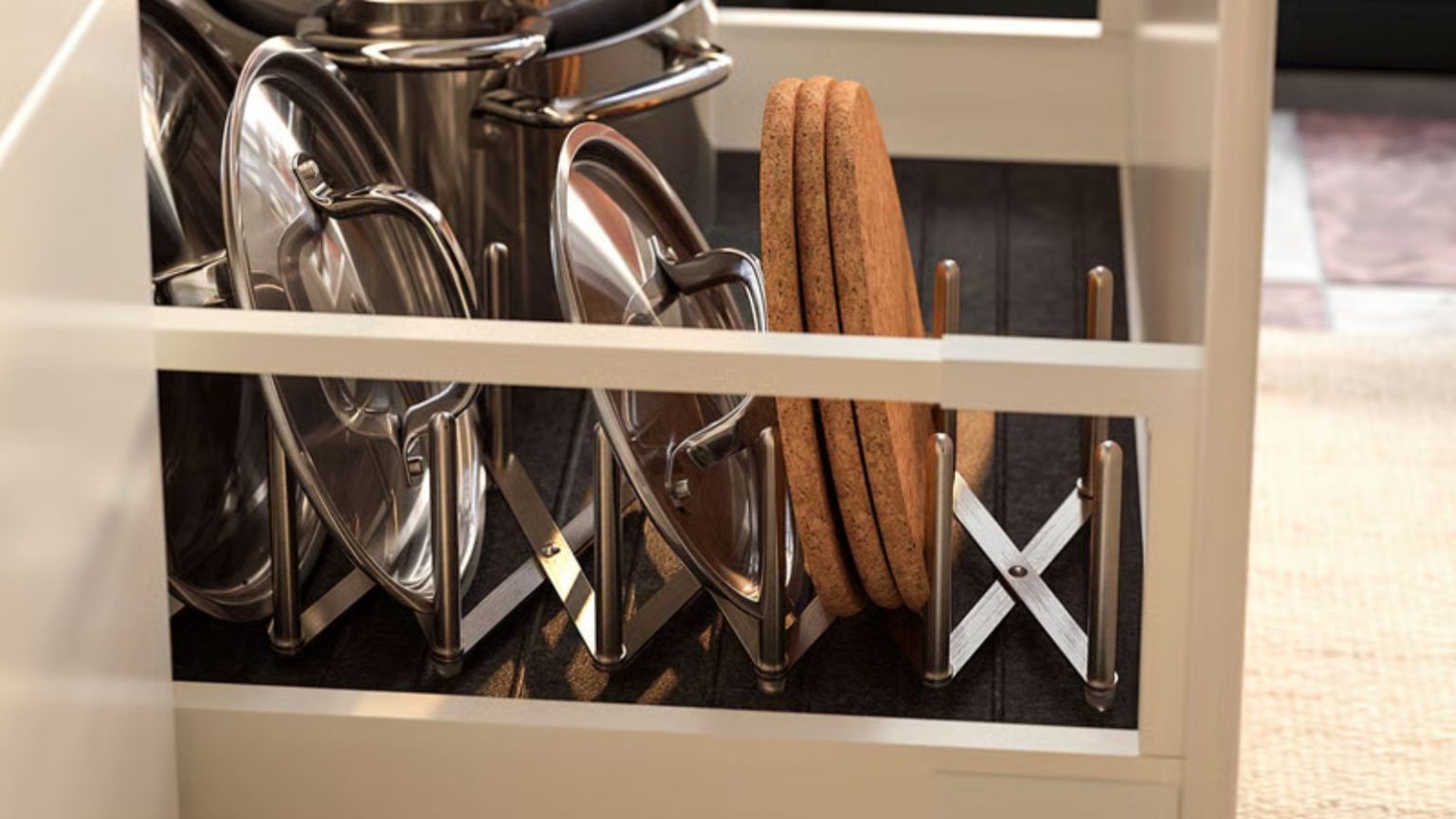 L’élégant support de couvercle de casserole en acier inoxydable à 7 $ d’IKEA transforme les armoires bondées en un espace de rangement organisé et peu encombrant An expanding stainless steel pot lid organizer in a kitchen drawer with pan lids stacked inside.