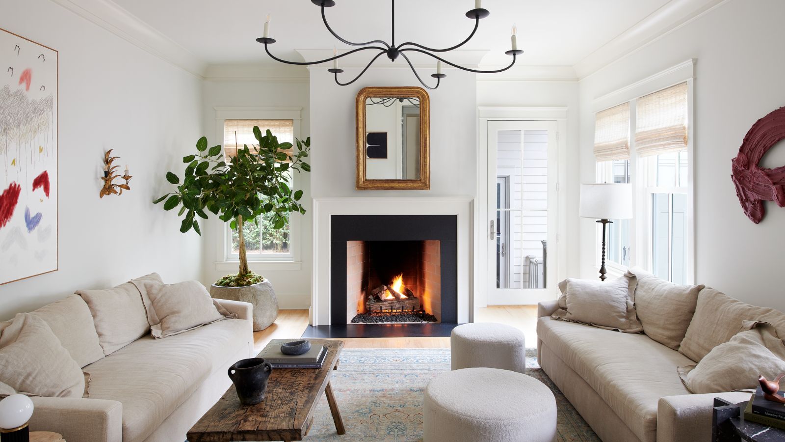 Un salon blanc avec des murs et un plafond blancs, deux canapés beige clair, une table basse en bois vintage, un tapis neutre et une décoration transitionnelle. 