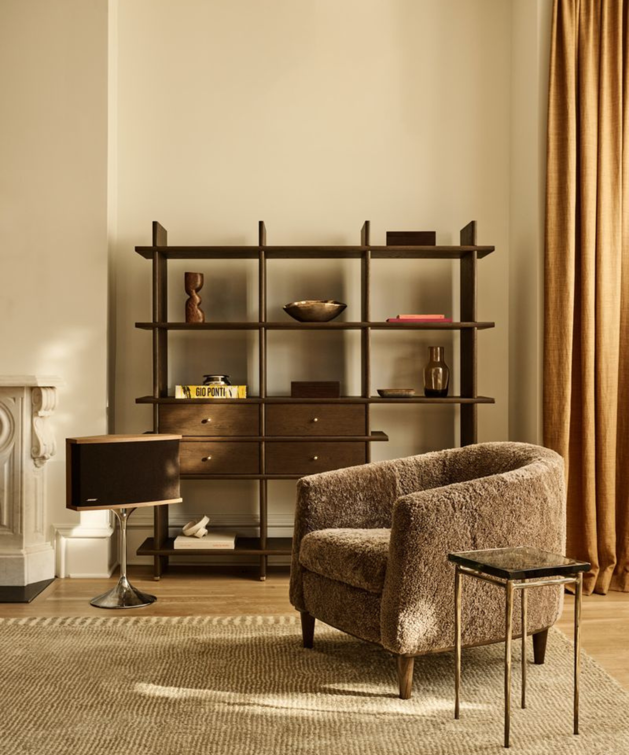 un coin salon avec une chaise en peau de mouton marron, une petite table d'appoint et une bibliothèque en chêne foncé