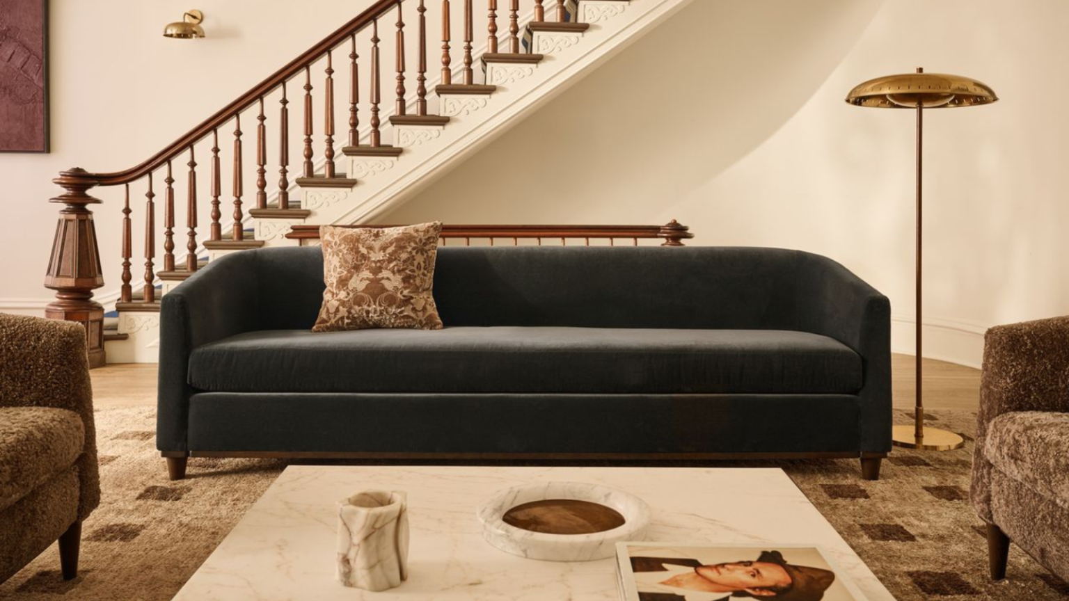 an elegant living room with a blue couch, a brass floor lamp, and a marble coffee table