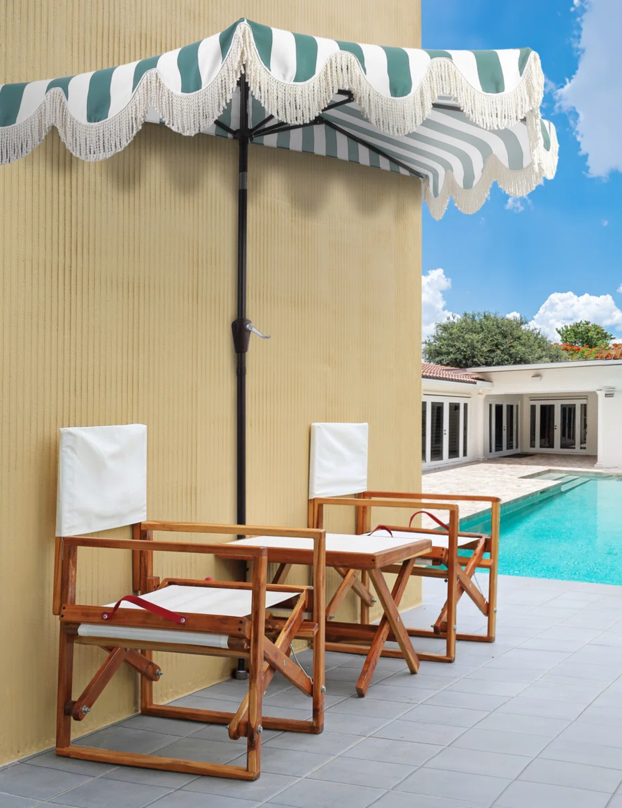 Demi-parapluie à rayures avec une bordure festonnée à franges en lingots ombrageant deux chaises d'extérieur en bois à côté d'une terrasse