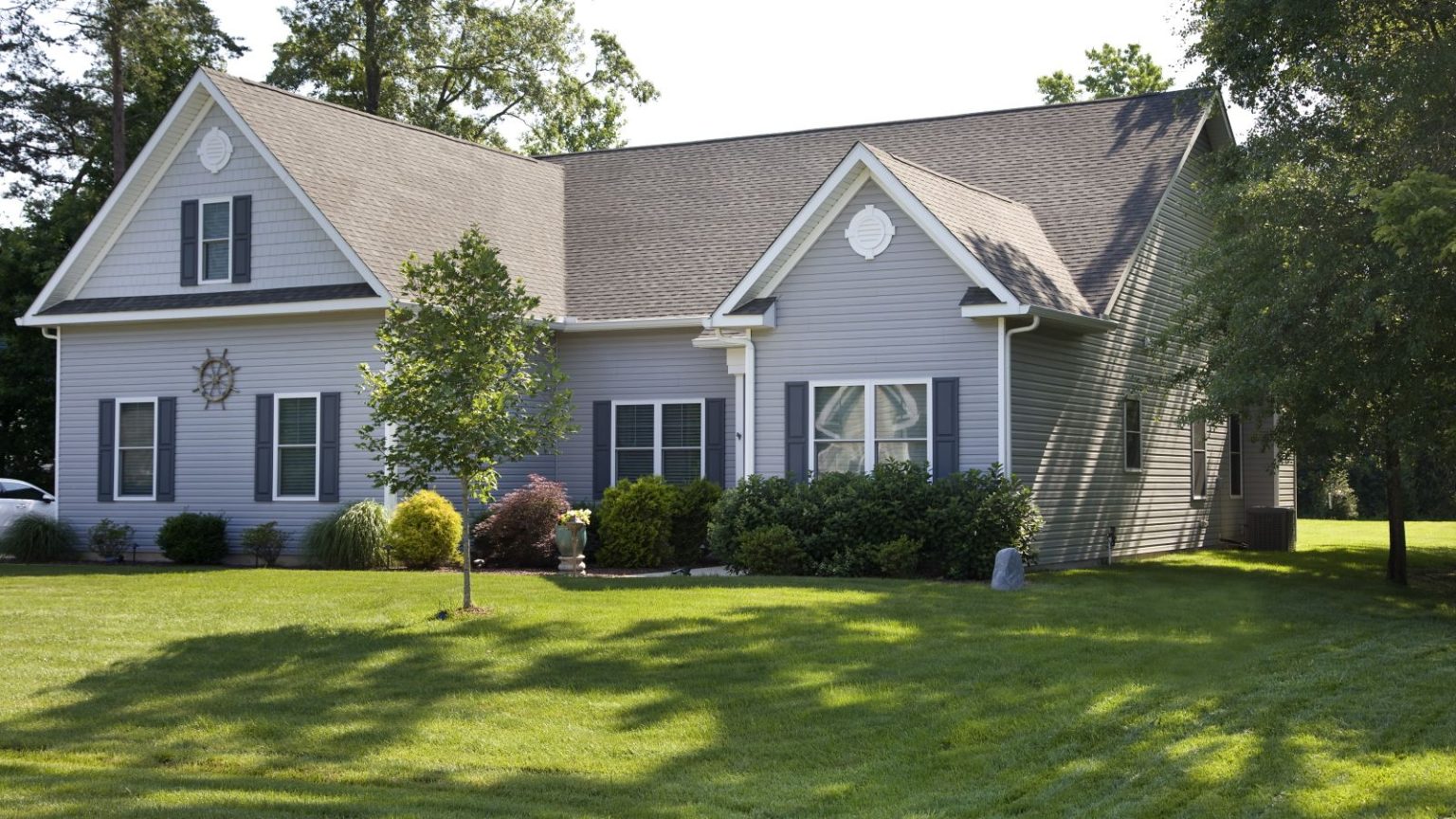 3 raisons pour lesquelles votre pelouse semble pire en juin – et comment les experts recommandent de la redresser A suburban home with a lush, green front lawn in the summer