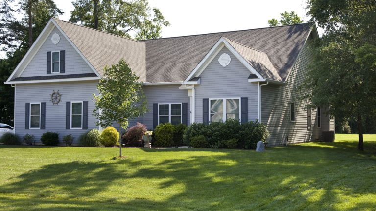 3 raisons pour lesquelles votre pelouse semble pire en juin – et comment les experts recommandent de la redresser A suburban home with a lush, green front lawn in the summer