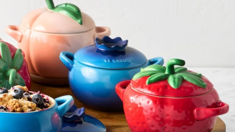 A set of three Le Creuset coquettes, shaped like a strawberry, a blueberry, and a peach