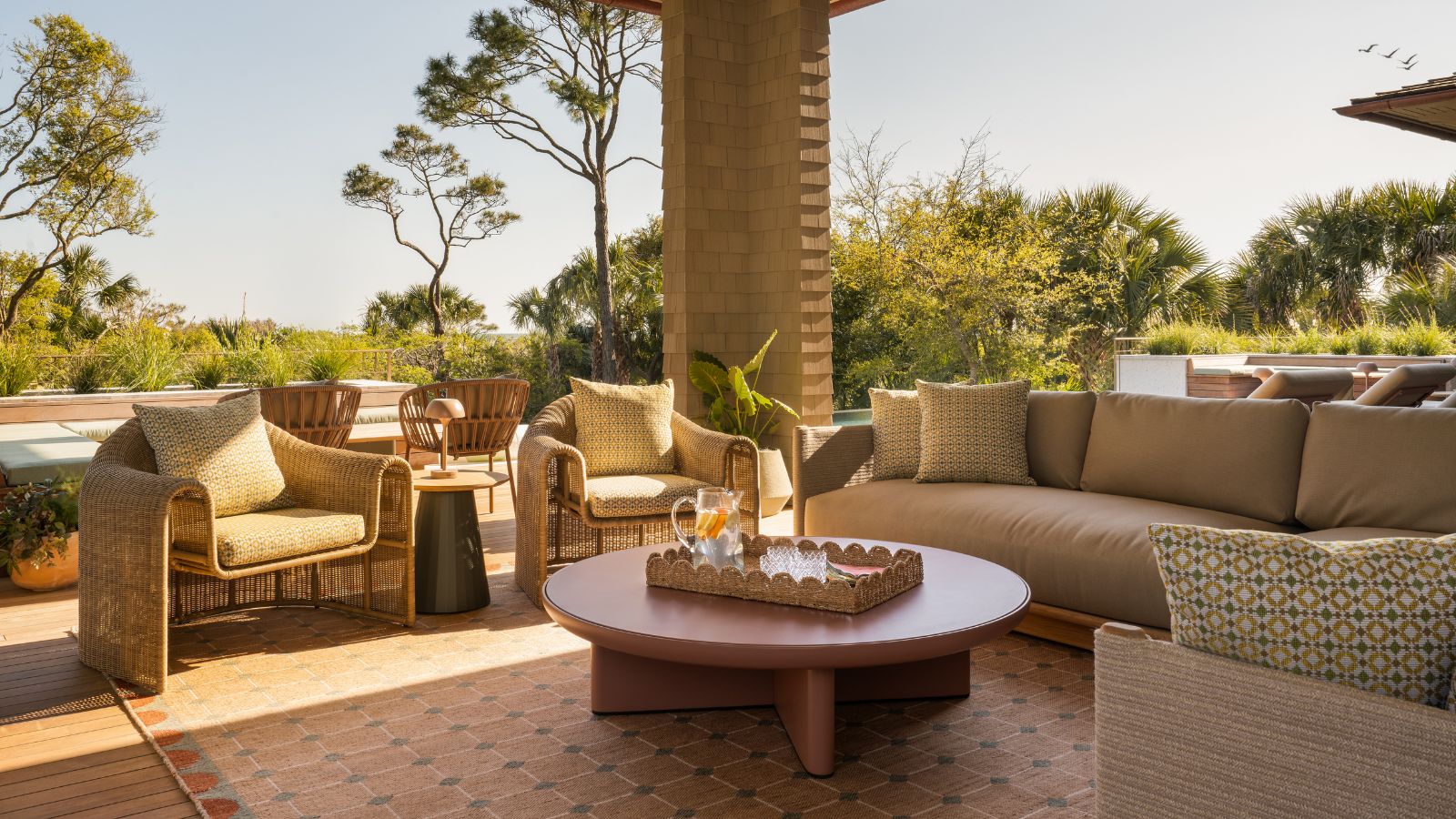 Salon extérieur avec chaises corbeille, canapé et tapis d'extérieur dans une palette terreuse