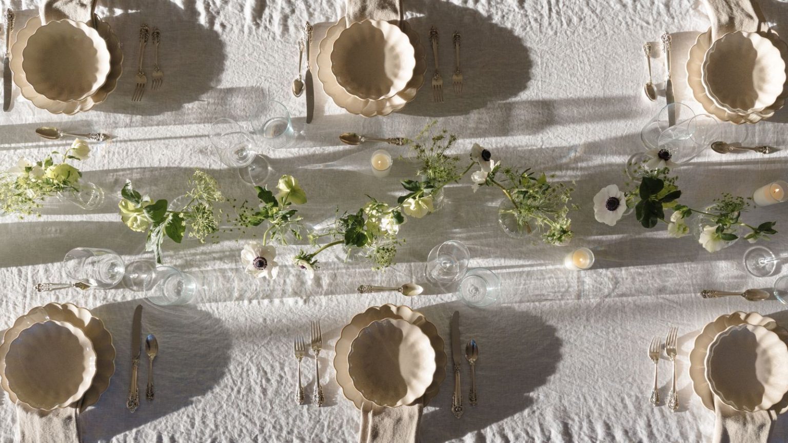 5 erreurs qui donnent à votre table extérieure un aspect bon marché – évitez-les cet été avec ces solutions faciles Outdoor tablescape with white linen tablescape, cream scalloped plates and bowls, a floral garland in the centre, and lit candles