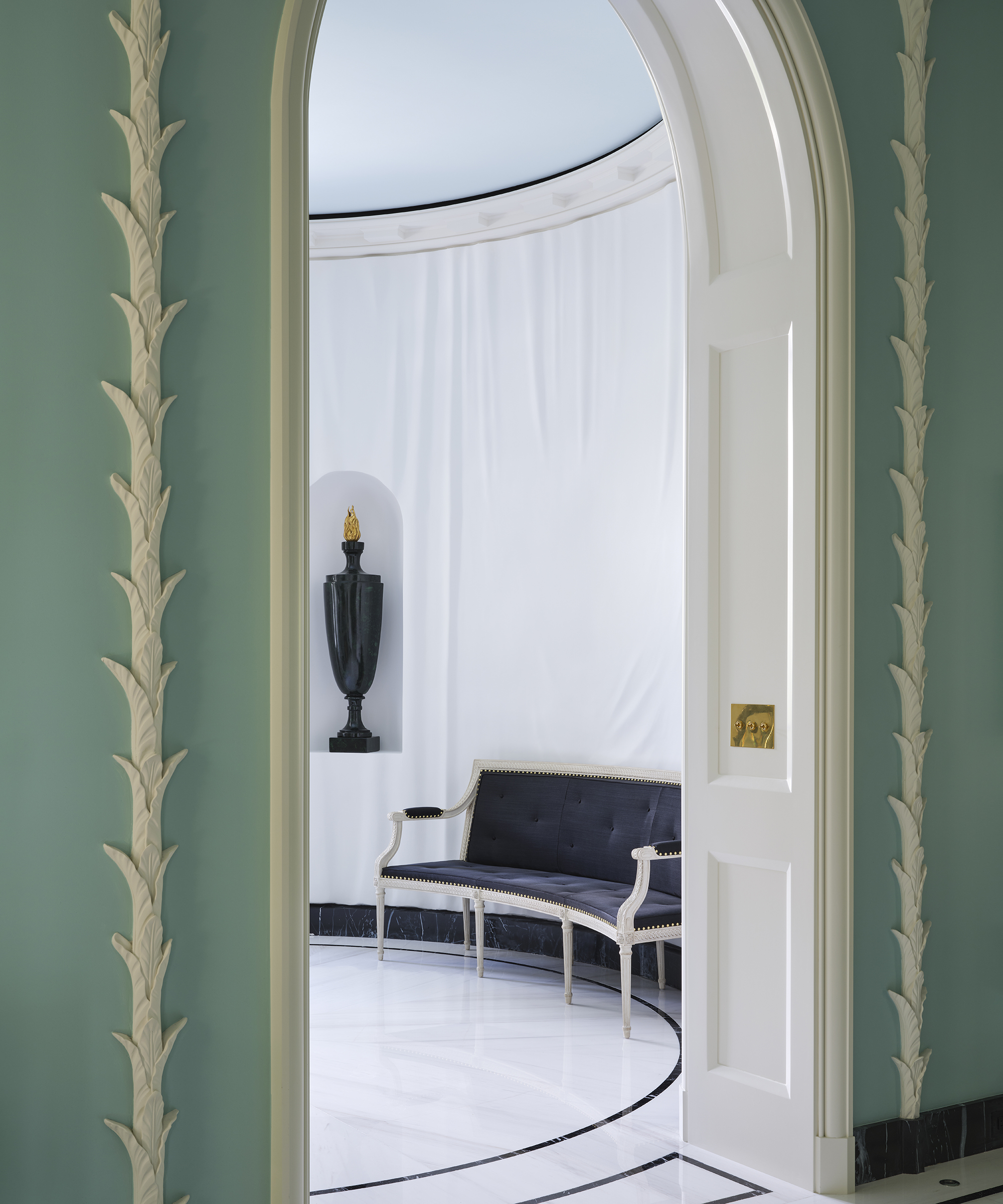 entrée incurvée blanche avec un canapé bleu et un vase dans une niche dans le mur