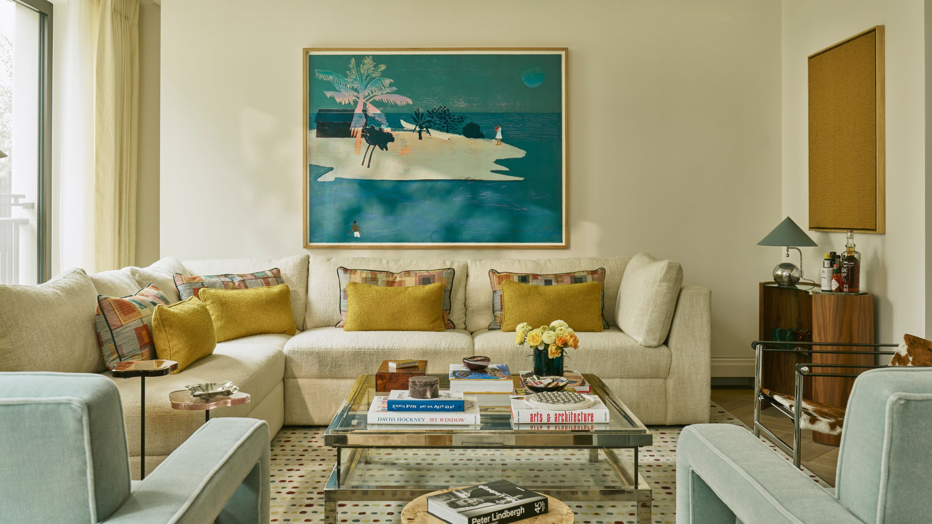 un salon londonien neutre avec un grand canapé sectionnel crème et une palette de couleurs bleu et jaune