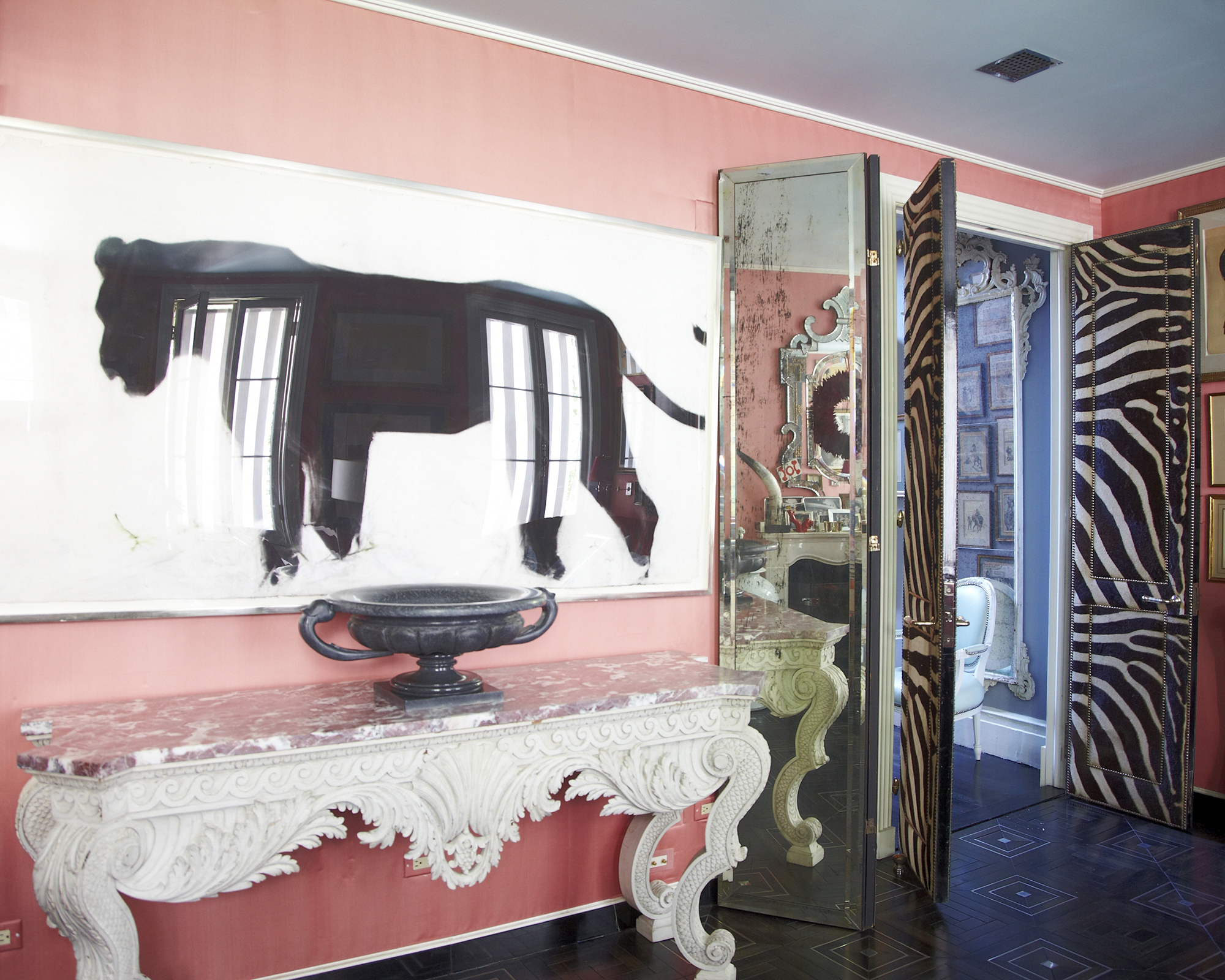 salon rose avec console blanche sous une grande œuvre d'art graphique en noir et blanc