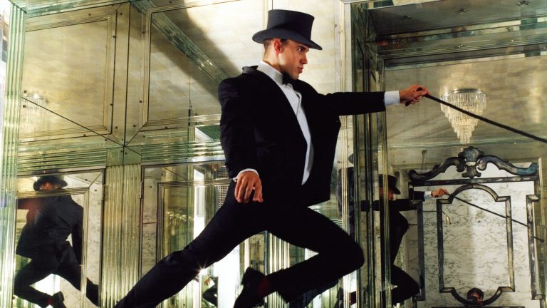 « C’est très libérateur de ne pas être attaché aux objets de votre maison » : pourquoi le designer Miles Redd évolue vers une nouvelle phase décorative fraîche et aérée Miles Redd wearing a top hat and black suit jumping in the air in the middle of a mirrored room