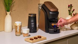Lavazza vient de réinventer le café en portion individuelle avec des dosettes sans plastique – et les amateurs de café sont obsédés The Lavazza Tablì coffee machine in black and copper, with three no-plastic coffee tabs on a wooden tray beside it
