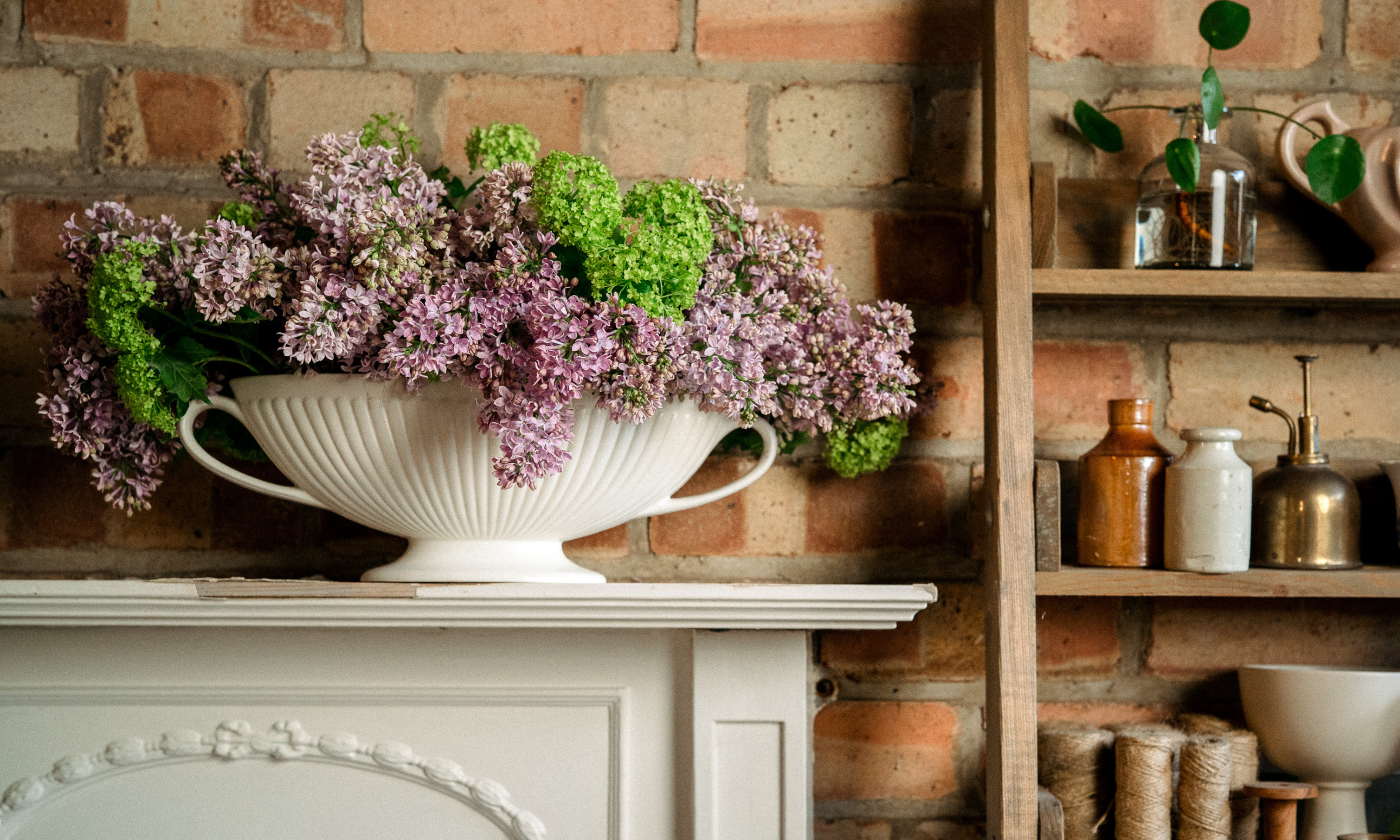Conception florale avec abondance de lilas et de vert viburnum opulus roseum sur la cheminée devant le mur de briques