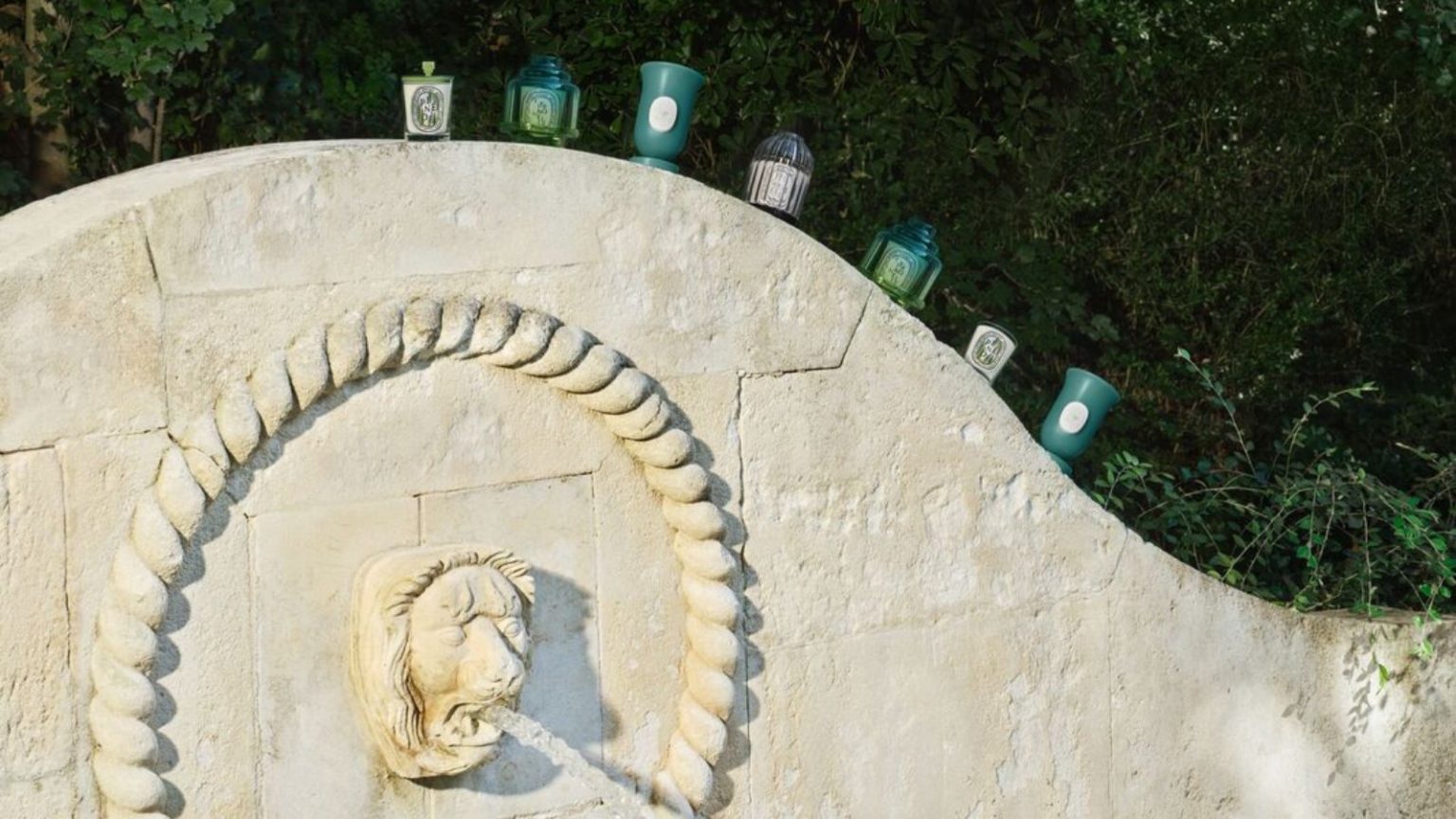 La dernière bougie Diptyque présente un avantage estival inattendu : c’est la façon élégante dont je repousse les moustiques lorsque j’héberge en plein air cet été Diptyque summer collection photographed on a curved wall with greenery behind.