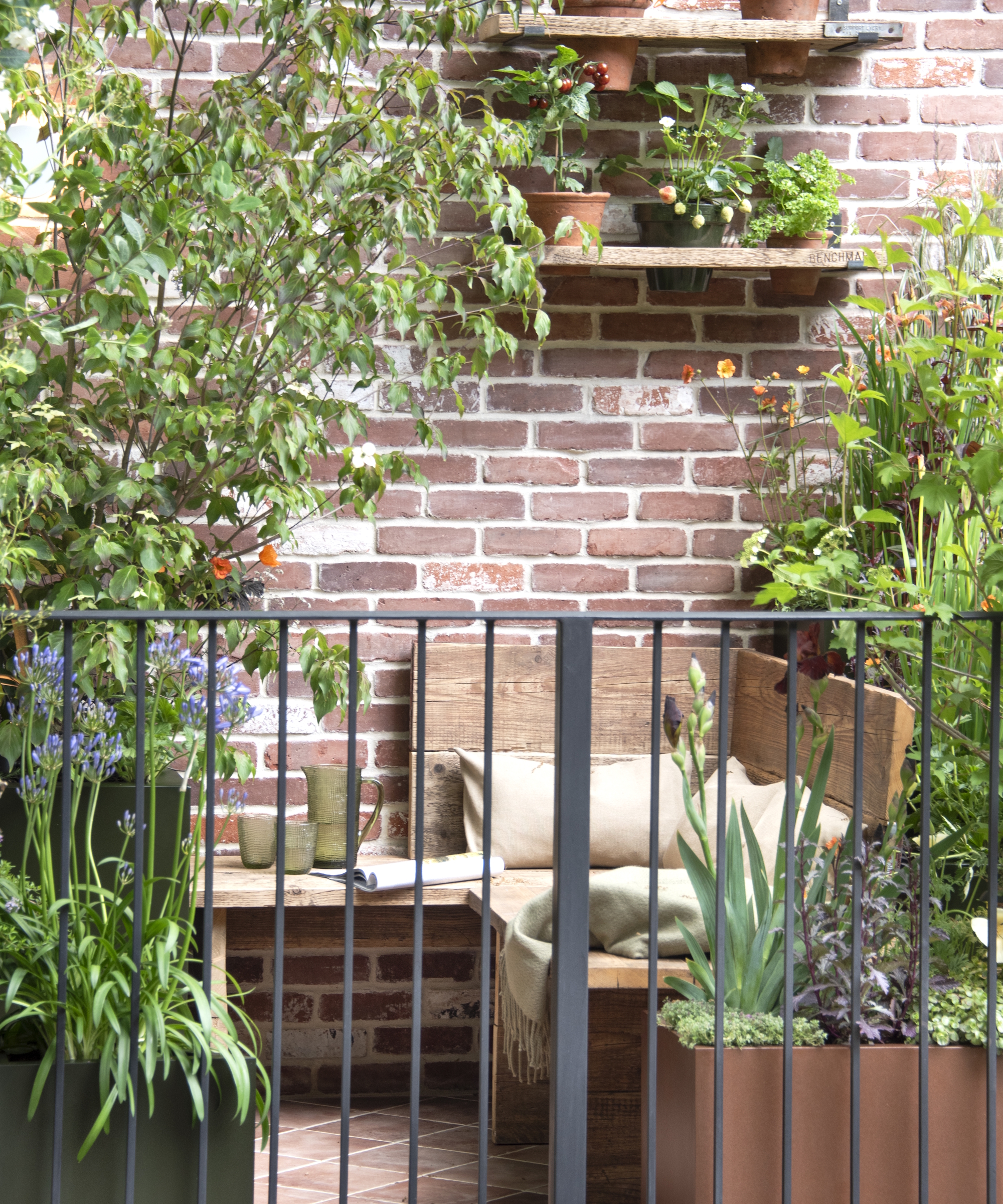 Un jardin avec balcon au RHS Chelsea Flower Show 2026, doté de sièges en bois entourés de plantes en pot
