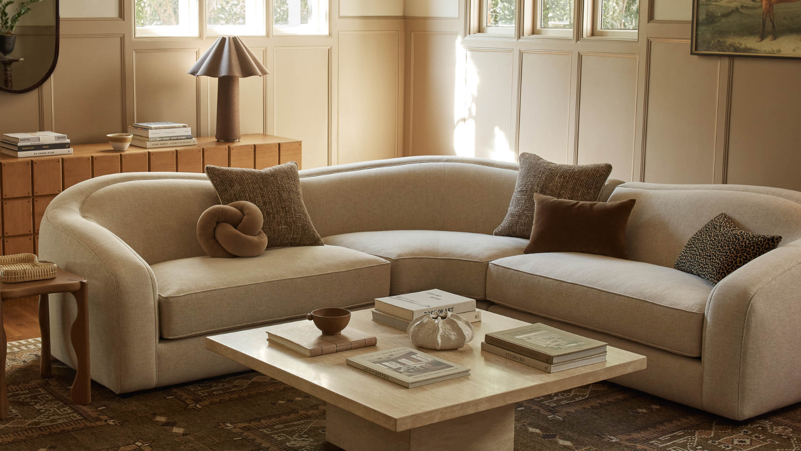 un canapé blanc cassé avec plusieurs oreillers et une table basse carrée avec un décor dessus