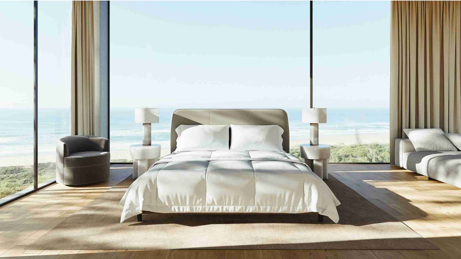 Cadre de lit Saatva dans une grande chambre lumineuse avec des baies vitrées avec une plage derrière. Le sol est en bois clair et de chaque côté du lit se trouvent deux tables de nuit et lampes blanches assorties.
