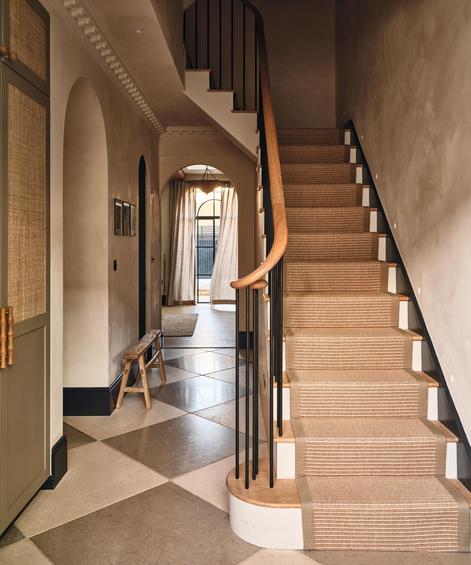 une entrée londonienne avec un sol carrelé en damier, un escalier en chêne blanc et en métal noir avec des murs blanchis à la chaux