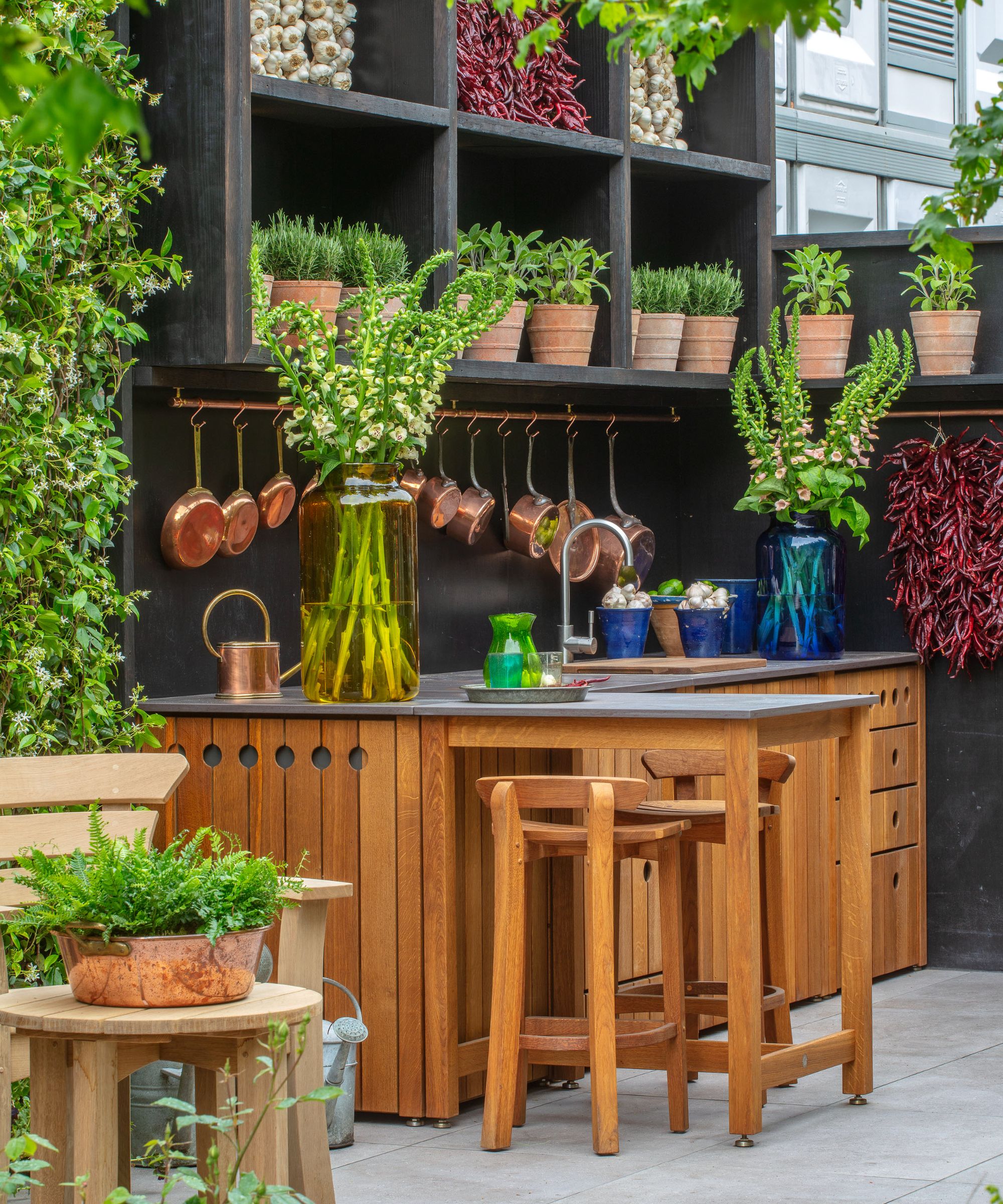 Bar extérieur en bois avec étagères derrière avec des pots d'herbes en terre cuite