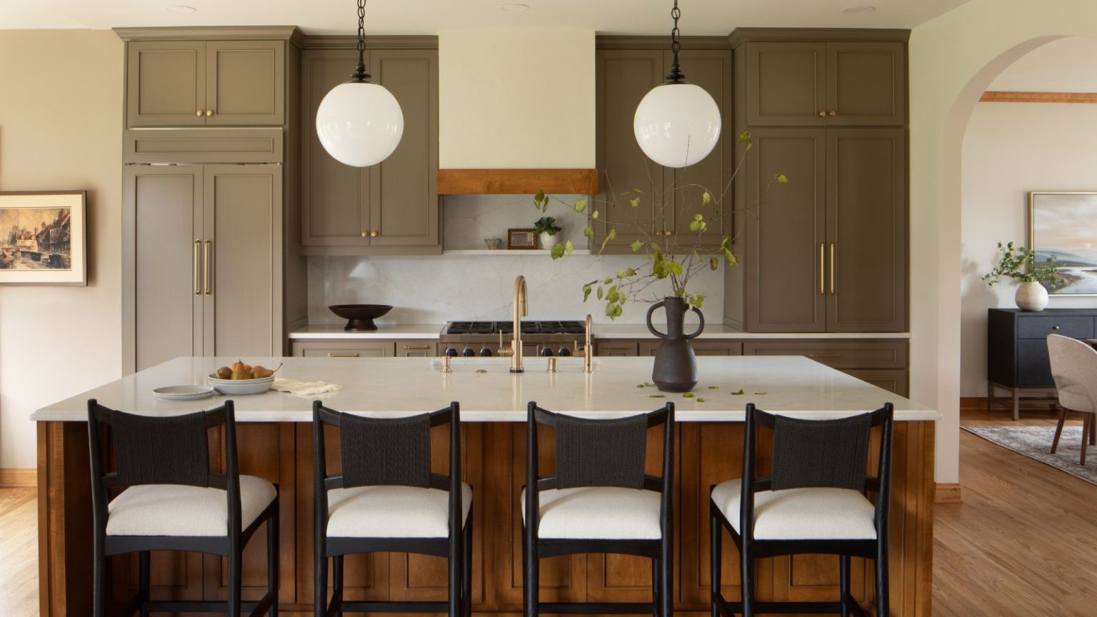 Les couleurs « sales » dans la cuisine sont partout en ce moment – Pourquoi les designers aiment ces tons sourds pour leur look étonnamment luxueux A large kitchen with muddy green cabinets and a wooden island