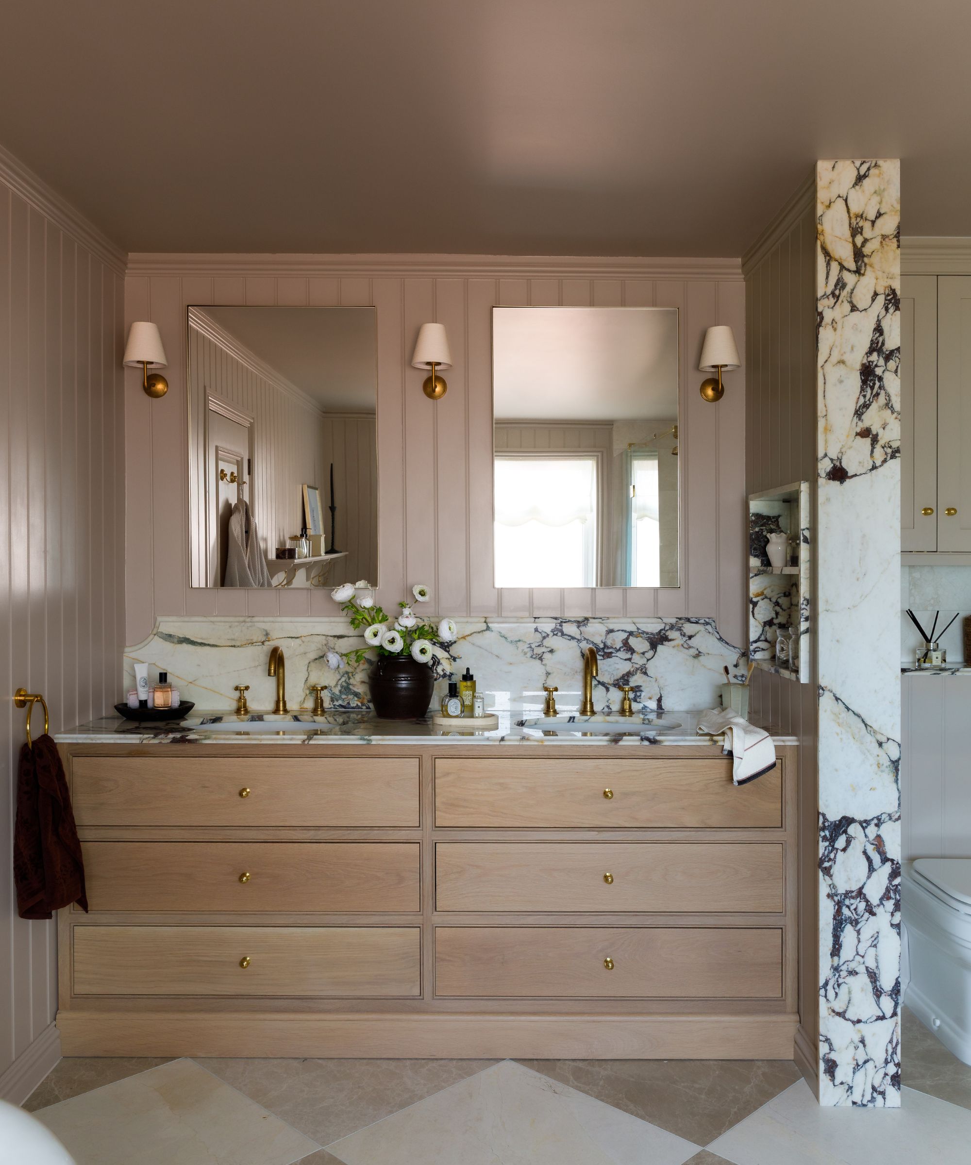 Salle de bain avec souffle d'éléphant par Farrow &amp; Murs peints en boule, meuble sous-vasque double vasque avec plan de travail en marbre, tiroirs en bois intégrés en dessous et deux miroirs avec appliques de chaque côté.
