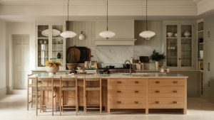 Une approche non conventionnelle du design traditionnel a transformé cette cuisine familiale en un espace chaleureux, superposé et sociable. A large family kitchen with pale green walls and cabinetry paired with a wooden island